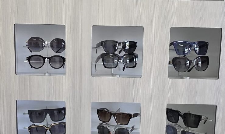 Wall of sunglasses in lit display niches at Reel Optics
