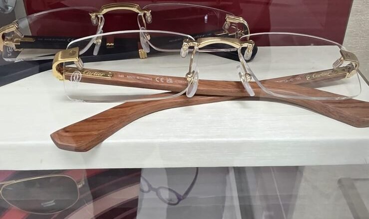 Rimless Cartier frames with wooden temples above a shelf of Ray-Ban frames
